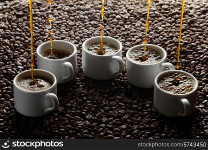 Pouring coffee into five cups on coffee beans
