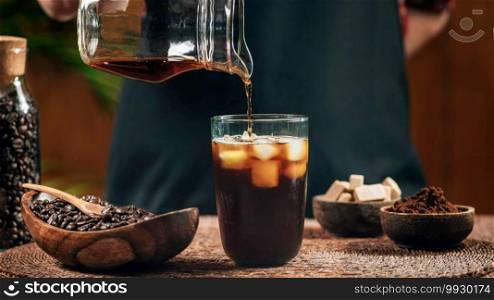Pouring cold brew iced coffee in glass cup with ice cubes