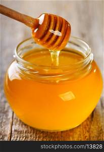 pouring honey from wooden stick into jar