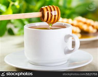 pouring honey into cup of tea
