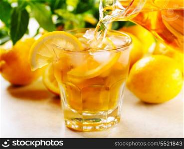 pouring ice tea into glass with slices of lemon