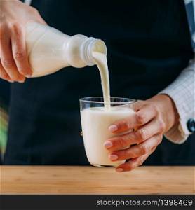 Pouring Kefir into glass, a healthy fermented dairy superfood drink, rich in natural probiotics Lacto and Bifido Bacterium