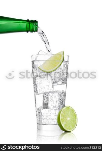 Pouring lemonade soda drink sparkling water from bottle to glass with lime