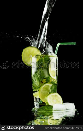 Pouring mojito. Pouring fresh mojito cocktail in glass isolated on black background