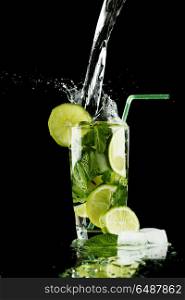Pouring mojito. Pouring fresh mojito cocktail in glass isolated on black background