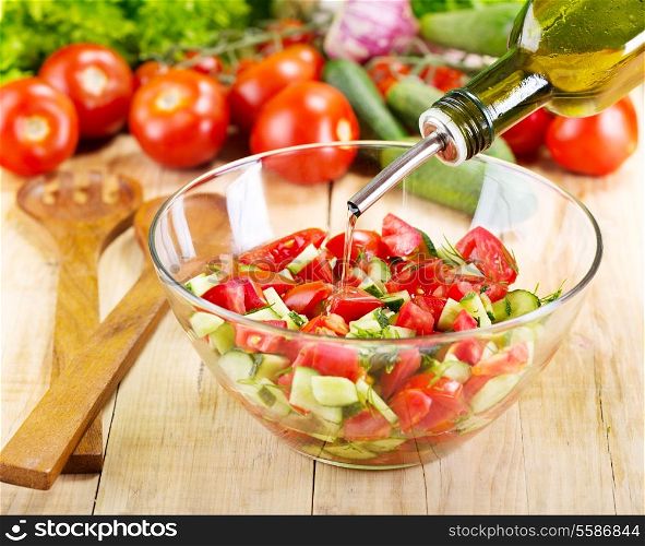 pouring oil into bowl of vegetable salad