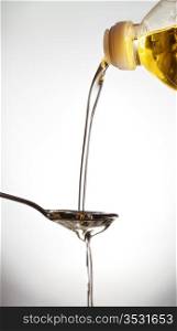 pouring olive oil on spoon, gray background