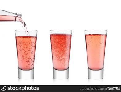 Pouring pink soda lemonade from bottle to glass on white background