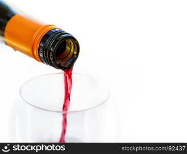 Pouring red wine from bottle into the wineglass on white background. Blurred concept