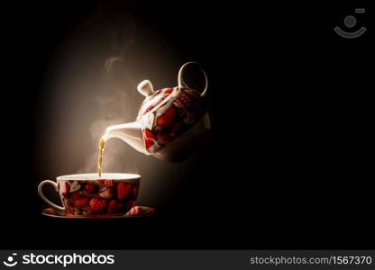 Pouring steaming tea into heart design cup from levitating porcelain teapot. Cup of tea from levitating teapot