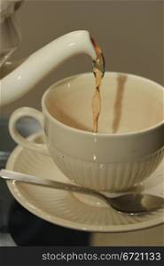 Pouring tea in classic white teacup, close up