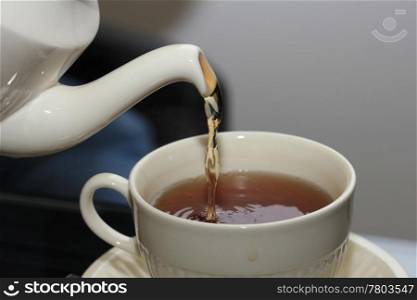 Pouring tea in classic white teacup, close up