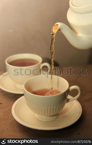 Pouring tea in classic white teacups, close up