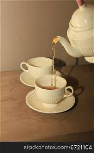 Pouring tea in classic white teacups, close up