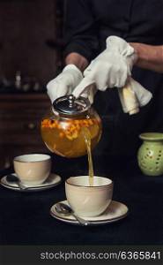 Pouring tea with sea buckthorn honey and herbs in glass teapot. Pouring tea with sea buckthorn