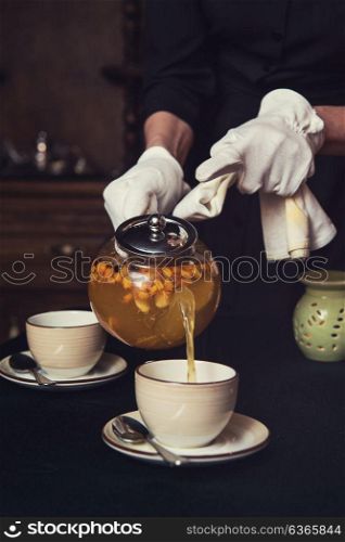 Pouring tea with sea buckthorn. Pouring tea with sea buckthorn honey and herbs in glass teapot