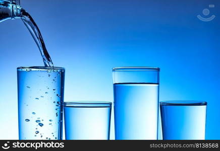 Pouring water into glass on blue background. . Pouring water into glass. 