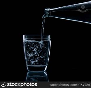 Pouring water on glass on over black background
