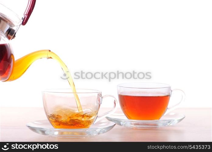 Pouting tea from teapot into the cup, isolated on white