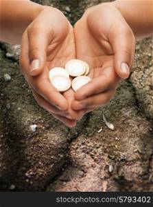 poverty, starvation, ecology and charity concept - closeup of female hands holding euro coins over ground background