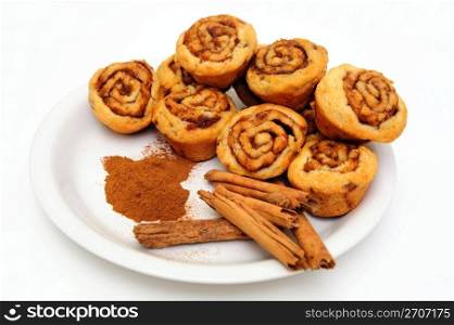 Powdered and stick cinnamon with freah baked mini cinnamon rolls on a white plate. Cinnamon Rolls