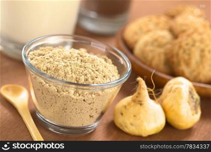 Powdered Maca or Peruvian ginseng (lat. Lepidium meyenii) in glass bowl with milk, chocolate drink, maca cookies and maca roots (Selective Focus, Focus one third into the maca powder). Maca Powder (Flour)