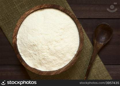Powdered or dried milk in wooden bowl, photographed overhead with natural light (Selective Focus, Focus on the top of the milk powder)