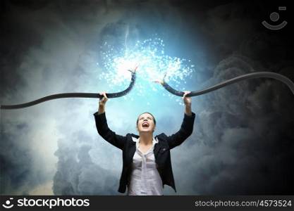 Power and energy. Image of businesswoman holding electrical cable above head