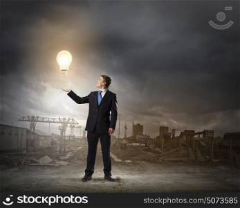 Power and energy. Young businessman holding light bulb in palm