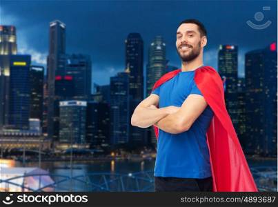 power and people concept - happy man in red superhero cape over night singapore city skyscrapers background. happy man in red superhero cape over night city