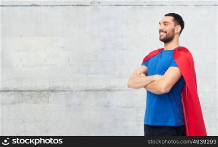 power and people concept - happy man in red superhero cape over gray concrete wall background. happy man in red superhero cape