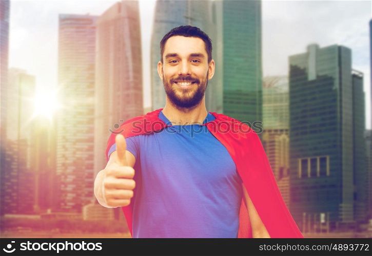 power and people concept - happy man in red superhero cape showing thumbs up over singapore city skyscrapers background. happy man in red superhero cape showing thumbs up