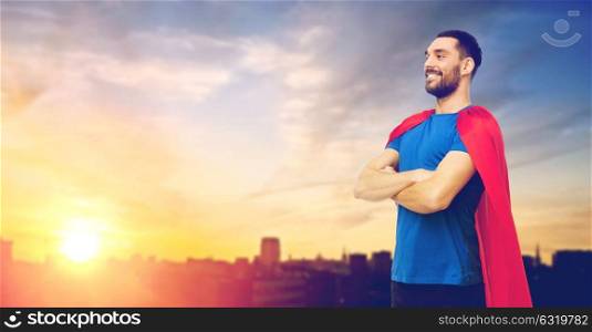 power and people concept - happy smiling man in red superhero cape over city and sun light background. man in red superhero cape over city background