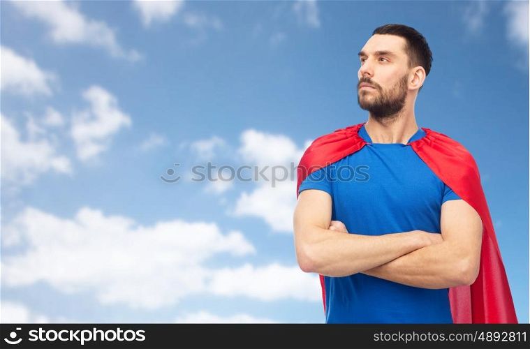 power and people concept - man in red superhero cape over blue sky and clouds background. man in red superhero cape over blue sky