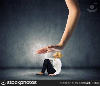 Power and pressure from above. Young woman sitting on floor and pressed by huge hand