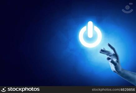 Power button. Hand pressing power button on blue background