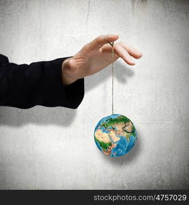 Power concept. Close up of male hand holding Earth planet on rope. Elements of this image re furnished by NASA