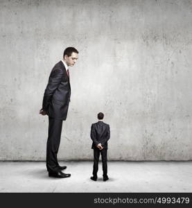 power in business. Big bossy businessman looking down at small businessman