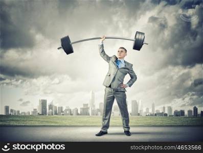 Power in business. Image of strong businessman lifting barbell above head with one hand