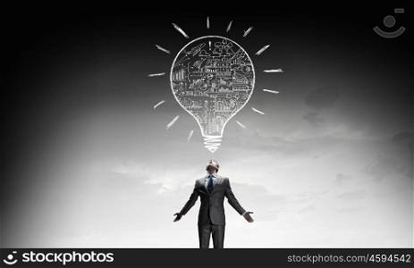 Power in idea. Businessman with hands spread apart and light bulb above
