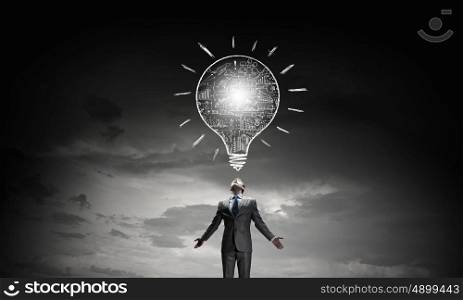 Power in idea. Businessman with hands spread apart and light bulb above
