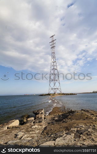 Power line support on the seashore in the solar morning