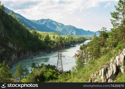 Power lines in the beautiful mountain landscape with a water stream in Altai, Siberia, Russia.. Power lines in the beautiful mountain landscape