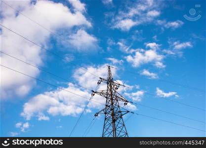 Power transmission line against the blue sky with white clouds.