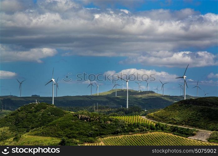 Power wind mills in a green hill against hazy sky in country side in Portugal.