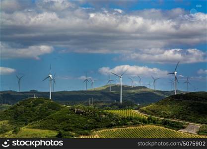 Power wind mills in a green hill against hazy sky in country side in Portugal.