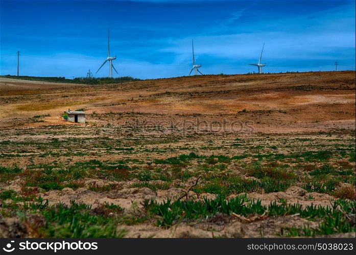 Power wind mills in the back of an agriculture field against hazy sky in Portugal.