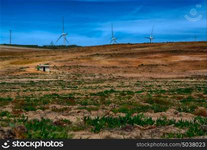 Power wind mills in the back of an agriculture field against hazy sky in Portugal.