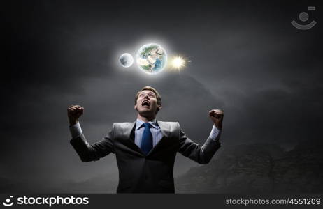 Powerful businessman. Emotional young businessman looking up and screaming. Elements of this image are furnished by NASA