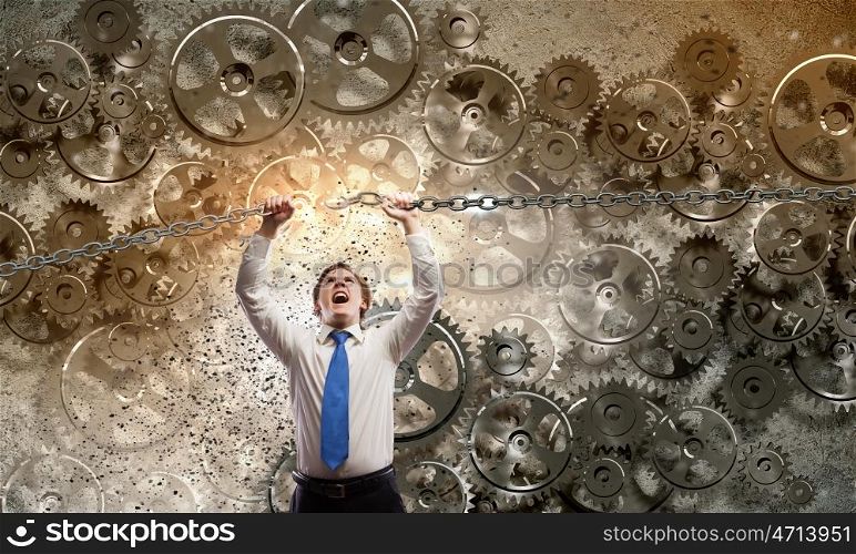 Powerful businessman. Young furious businessman breaking metal chain with hands